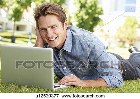 Stock Photo - Man using laptop in city park. Fotosearch