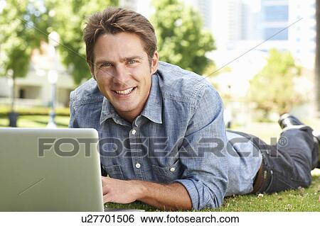 Man using laptop in city park View Large Photo Image Stock Photograph - Man using laptop in city park. Fotosearch