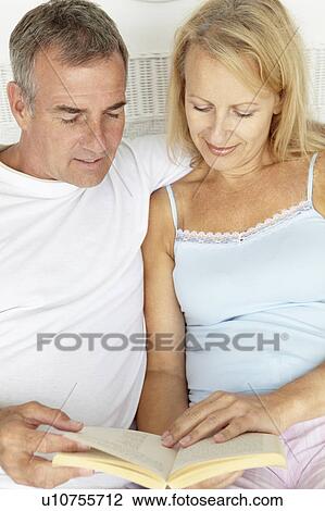 Stock Image - Mid age couple reading together. Fotosearch