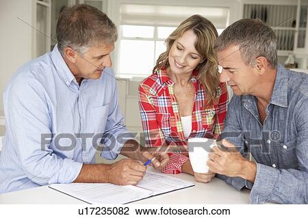 Stock Image - Mid age couple with financial advisor at home. Fotosearch