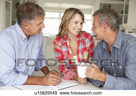 Stock Photo - Mid age couple with financial advisor at home. Fotosearch