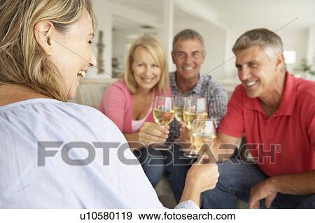 Mid age couples drinking together at home View Large Photo Image Stock Photo - Mid age couples drinking together at home. Fotosearch