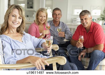 Stock Photo - Mid age couples drinking together at home. Fotosearch