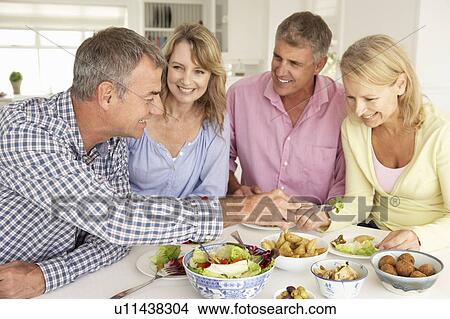 Mid age couples enjoying meal at home View Large Photo Image Picture - Mid age couples enjoying meal at home. Fotosearch