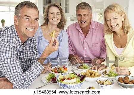 Mid age couples enjoying meal at home View Large Photo Image Picture - Mid age couples enjoying meal at home. Fotosearch