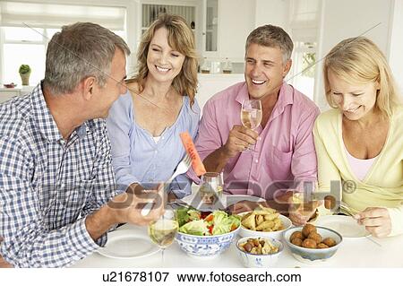 Mid age couples enjoying meal at home View Large Photo Image Stock Photo - Mid age couples enjoying meal at home. Fotosearch
