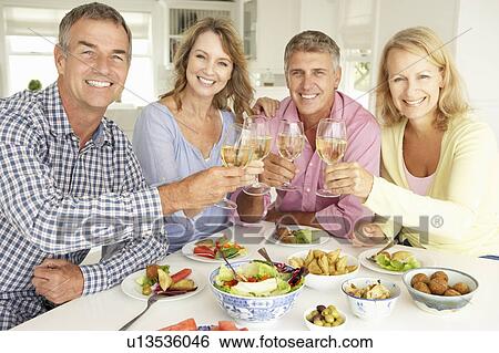 Stock Photograph - Mid age couples enjoying meal at home. Fotosearch