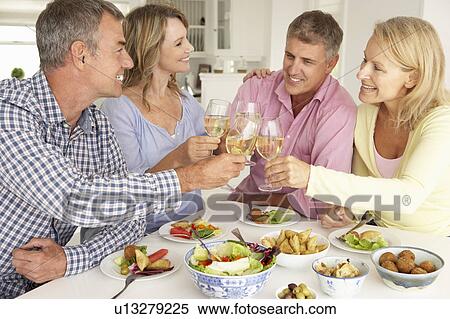 Stock Photography - Mid age couples enjoying meal at home. Fotosearch