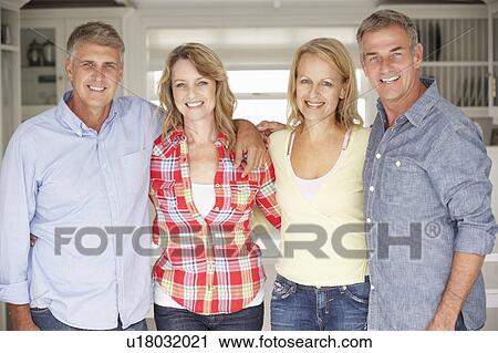 Stock Image - Mid age couples relaxing at home. Fotosearch
