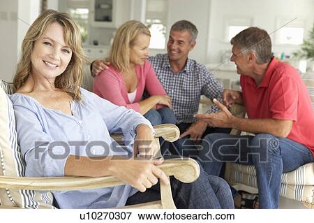 Stock Photo - Mid age couples relaxing at home. Fotosearch