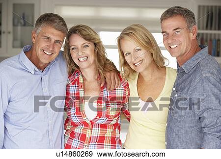 Stock Photo - Mid age couples relaxing at home. Fotosearch