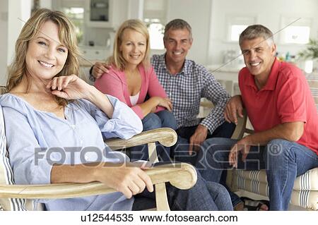 Stock Photography - Mid age couples relaxing at home. Fotosearch