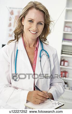 Stock Image - Mid age female doctor writing prescription. Fotosearch