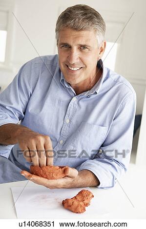 Stock Image - Mid age man clay modelling. Fotosearch