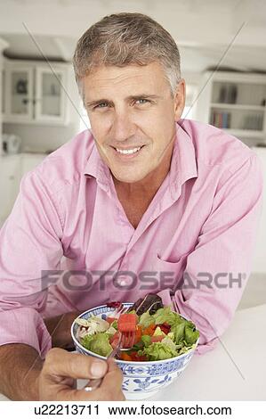 Stock Image - Mid age man eating salad. Fotosearch