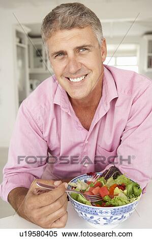 Stock Photography - Mid age man eating salad. Fotosearch