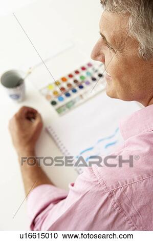 Stock Image - Mid age man painting with watercolors. Fotosearch