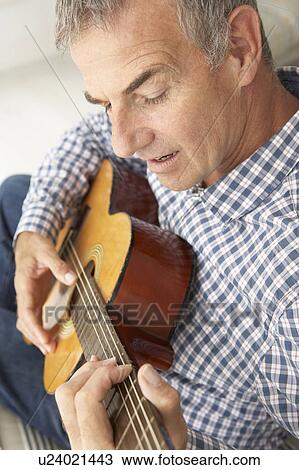 Stock Image - Mid age man playing acoustic guitar. Fotosearch