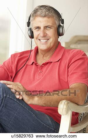 Stock Image - Mid age man wearing headphones. Fotosearch