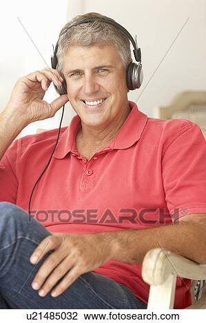 Stock Image - Mid age man wearing headphones. Fotosearch