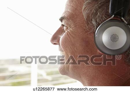 Stock Photo - Mid age man wearing headphones. Fotosearch