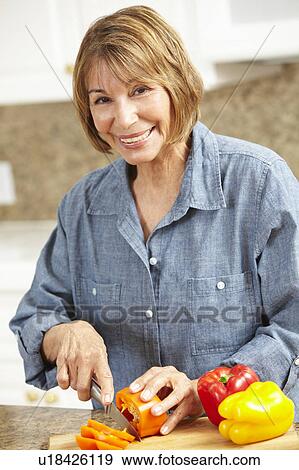 Mid age woman chopping vegetables View Large Photo Image Stock Photo - Mid age woman chopping vegetables. Fotosearch
