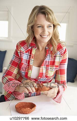Stock Photograph - Mid age woman clay modelling. Fotosearch