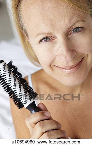 Mid age woman holding hairbrush View Large Photo Image Stock Image - Mid age woman holding hairbrush. Fotosearch