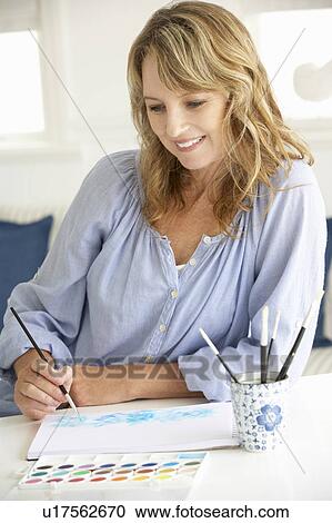 Stock Image - Mid age woman painting with watercolors. Fotosearch