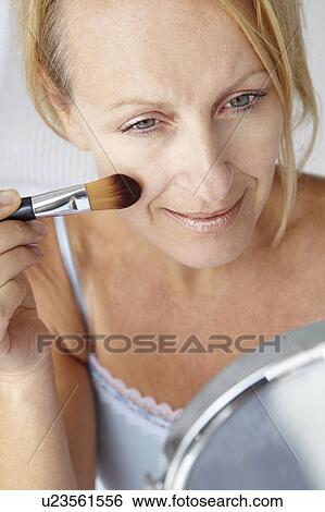 Stock Photograph - Mid age woman putting on make-up. Fotosearch