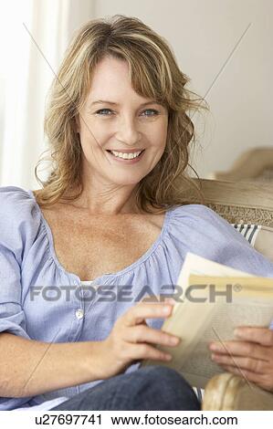 Stock Image - Mid age woman reading a book. Fotosearch