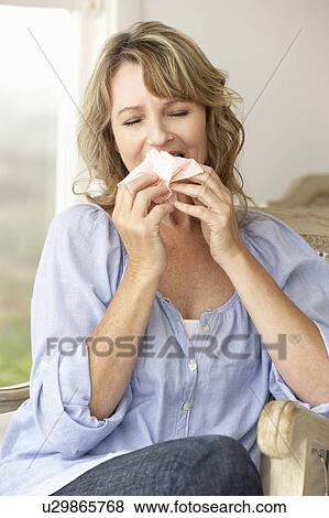 Mid age woman sneezing View Large Photo Image Stock Photo - Mid age woman sneezing. Fotosearch