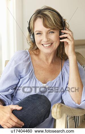Stock Image - Mid age woman wearing headphones. Fotosearch