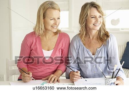 Stock Image - Mid age women painting with watercolors. Fotosearch
