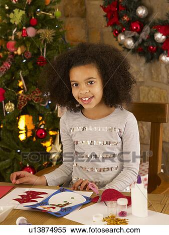 Stock Photography - Mixed race child making Christmas cards. Fotosearch