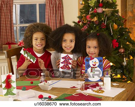 Stock Image - Mixed race children making Christmas cards. Fotosearch