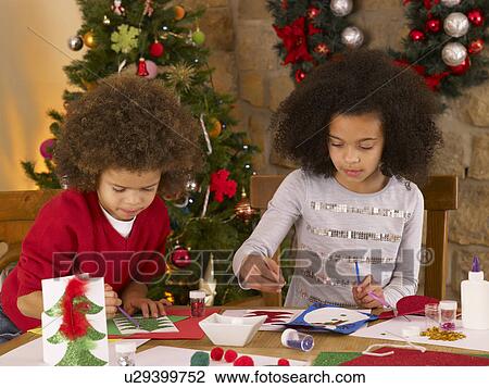 Stock Image - Mixed race children making Christmas cards. Fotosearch