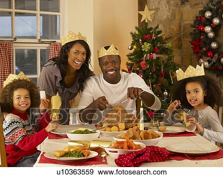 Stock Photo - Mixed race family having Christmas dinner. Fotosearch