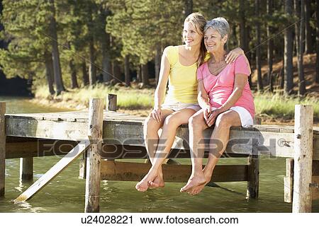 Mother and adult daughter sitting by lake View Large Photo Image Stock Image - Mother and adult daughter sitting by lake. Fotosearch
