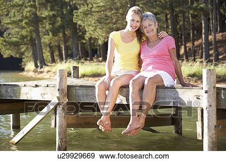 Stock Photo - Mother and adult daughter sitting by lake. Fotosearch