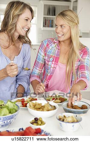 Stock Image - Mother and teenage daughter enjoying meal at home. Fotosearch