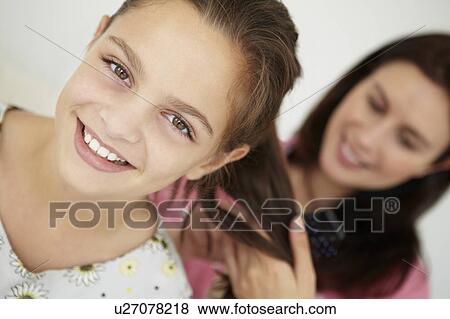 Stock Photo - Mother brushing daughter's hair. Fotosearch