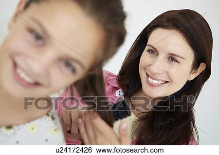 Stock Photograph - Mother brushing daughter's hair. Fotosearch