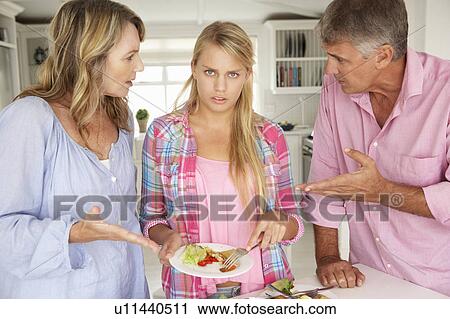 Stock Image - Parents making teenage daughter do chores at home. Fotosearch