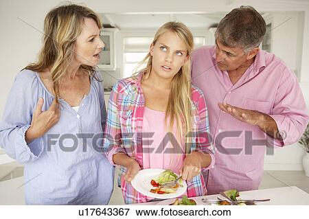 Stock Photo - Parents making teenage daughter do chores at home. Fotosearch