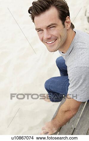 Picture - Portrait man sitting by beach. Fotosearch