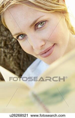 Stock Image - Portrait of young woman reading. Fotosearch