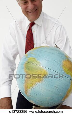 Stock Photograph - Senior businessman spinning globe. Fotosearch
