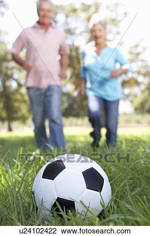 Stock Image - Senior couple playing football. Fotosearch