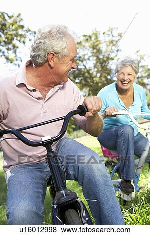Stock Photo - Senior couple playing on children's bikes. Fotosearch